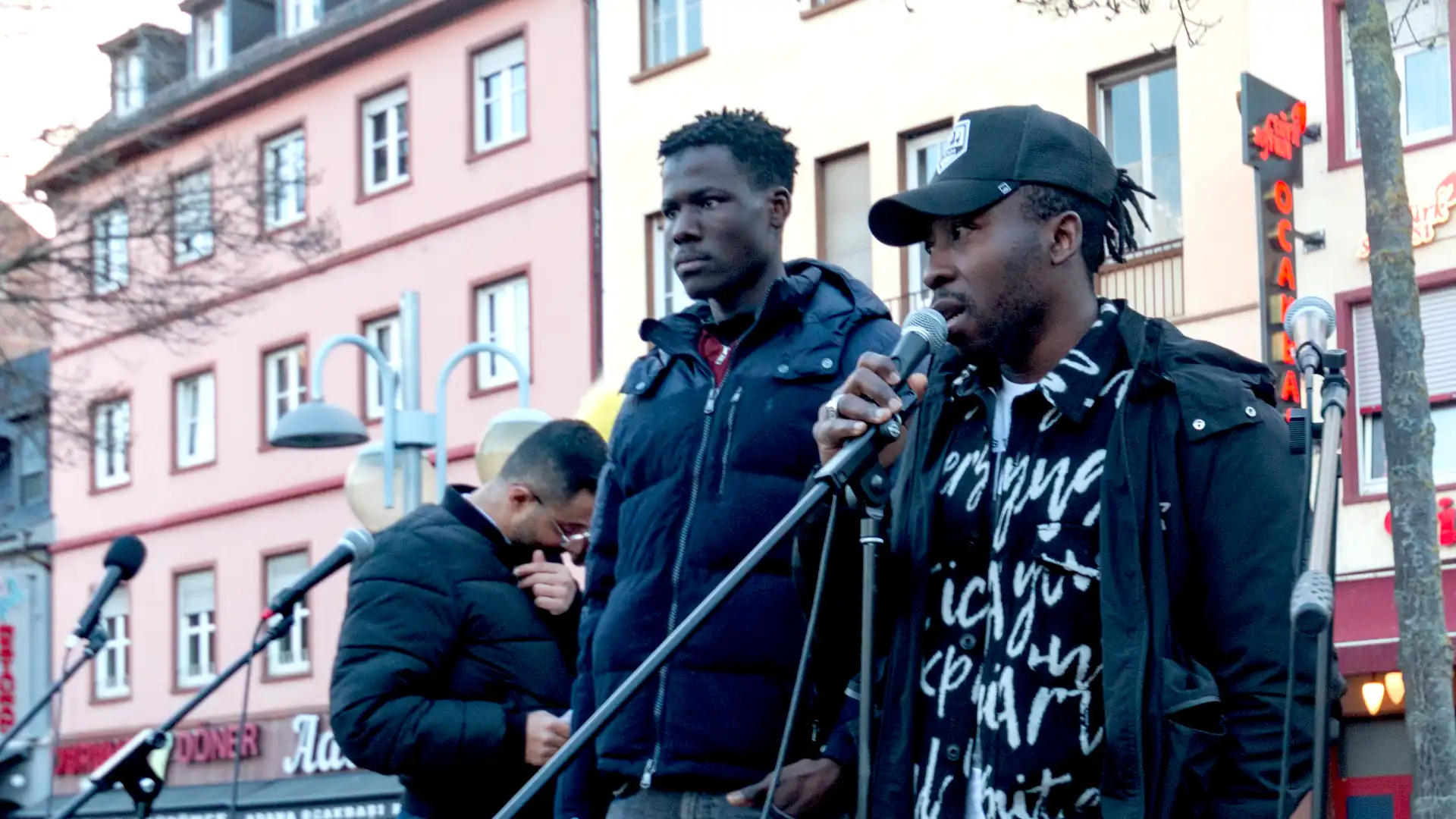 Die beiden Brüder von von Mohammed Drameh aus Dortmund stehen auf der Bühne. Im Hintergrund steht Emrah.