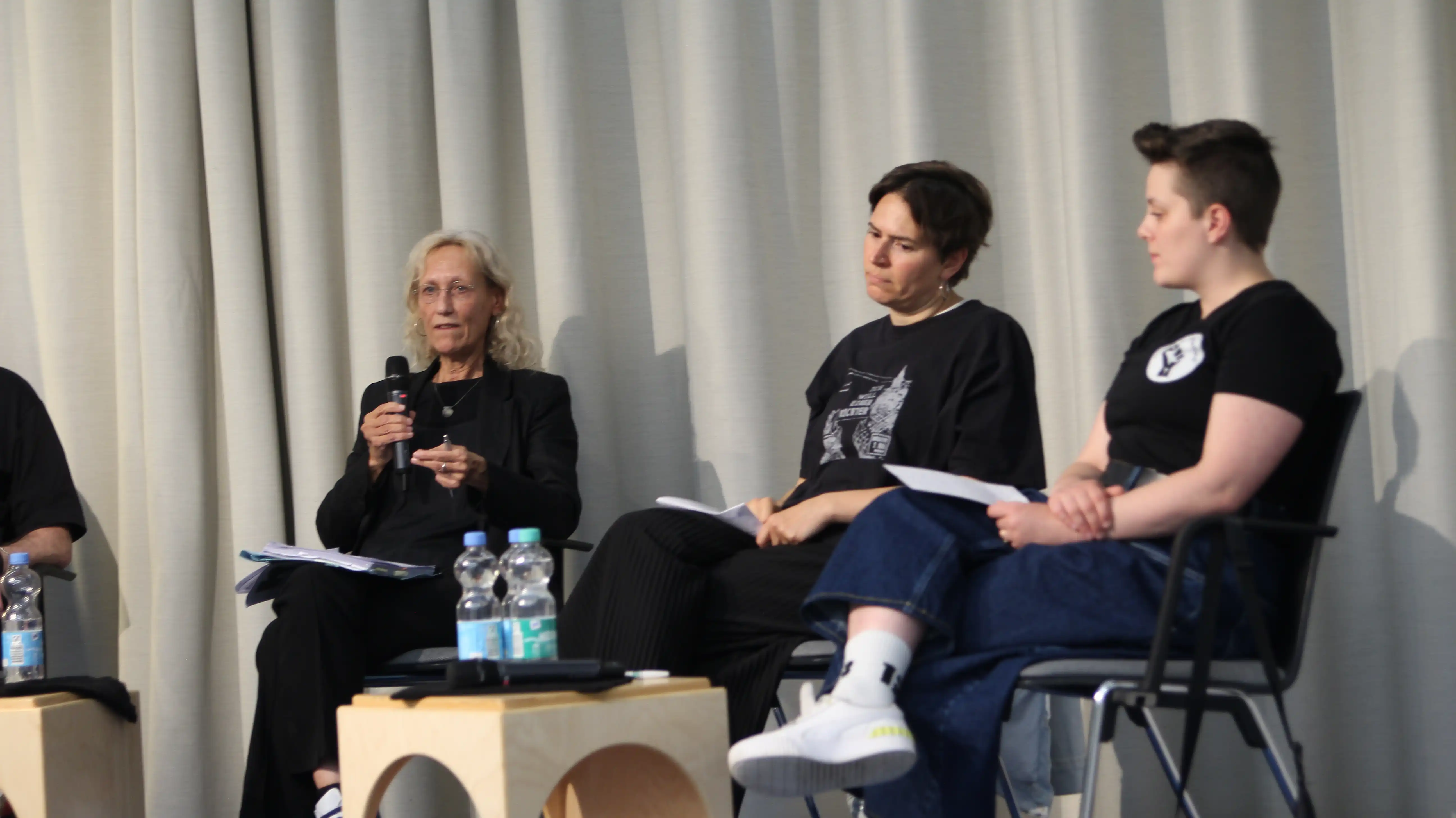 Von links nach Rechts sitzen Rechtsanwältin Beate Böhler, Dr. Sevda Can Arslan von der Initiative 2. Mai und Teddy von Justice for Mohamed. Sevda und Teddy tragen jeweils T-Shirts ihrer Initiativen